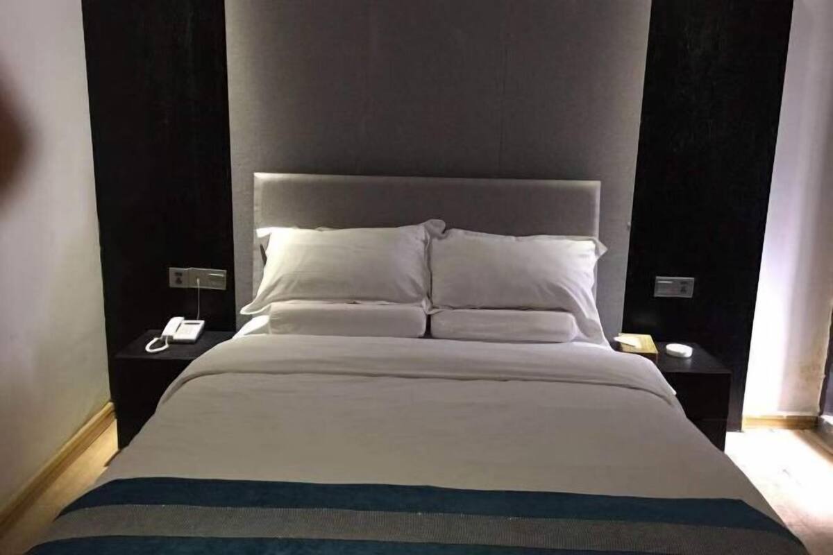 A hotel room with a large bed, two bedside tables, and a headboard.