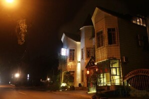 Um edifício com fachada curva, janelas iluminadas e portão gradeado.