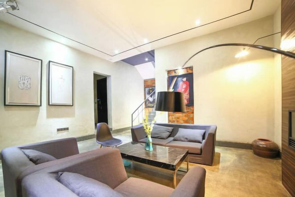 Ein modernes Wohnzimmer mit einer Couch, Sesseln, einem Couchtisch und Kunstwerken an den Wänden.