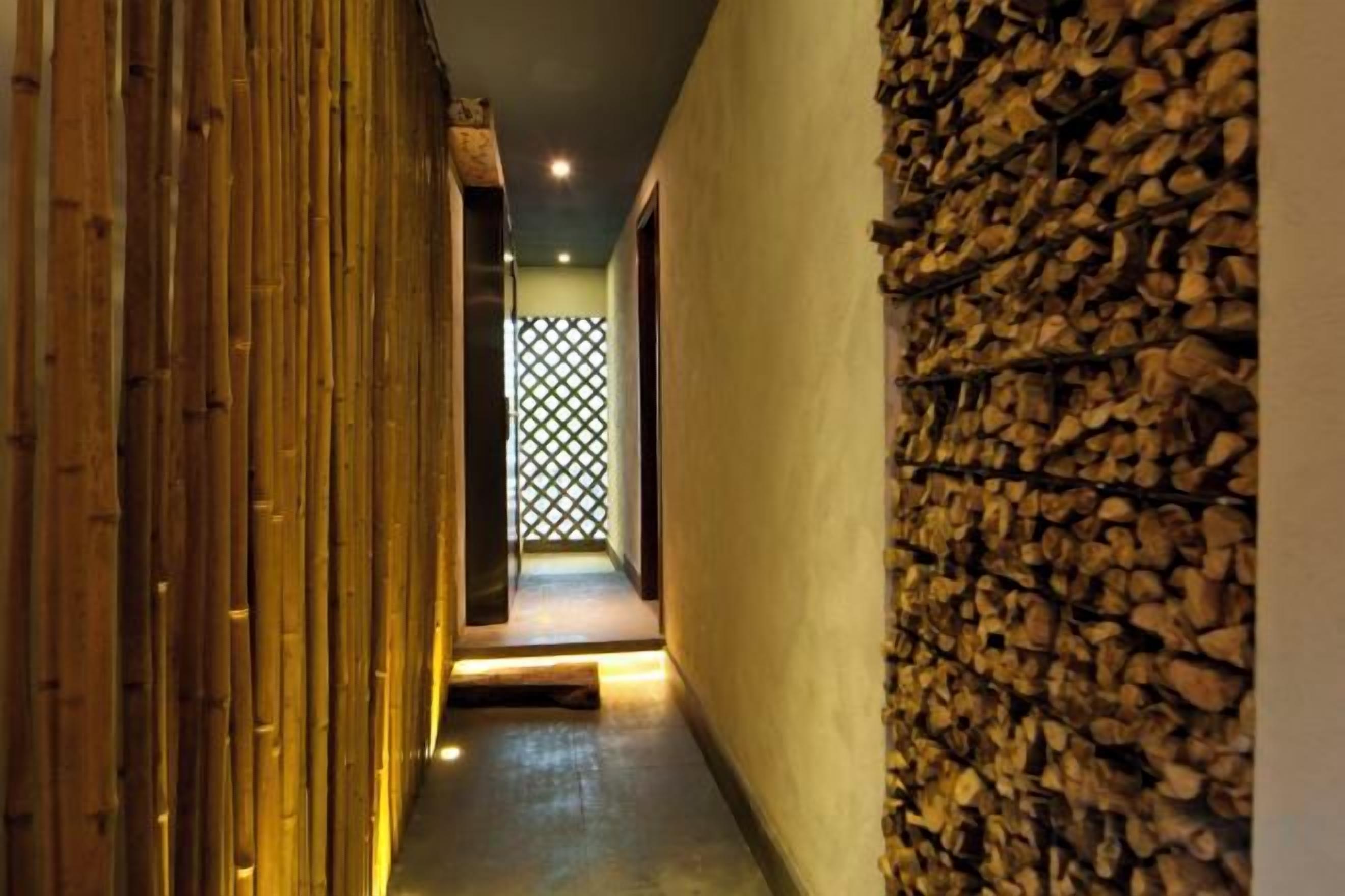 A corridor with a bamboo wall and a stone wall.