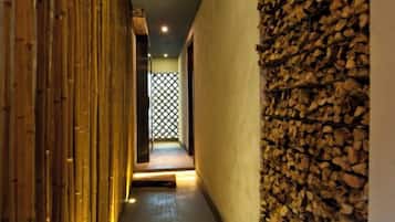A corridor with a bamboo wall and a stone wall.