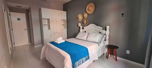 Quarto com uma cama, um guarda-roupa e uma mesa de cabeceira.