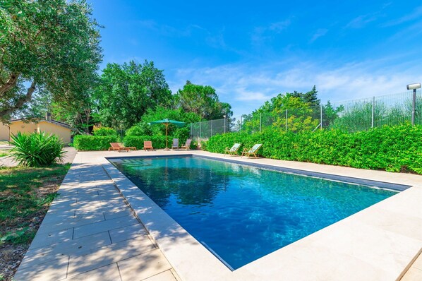 A rectangular swimming pool with a tiled deck, surrounded by lush greenery and a fenced area. - Wonderful private villa for 7 guests with private pool, WIFI, TV, patio and panoramic view (Urbisaglia)