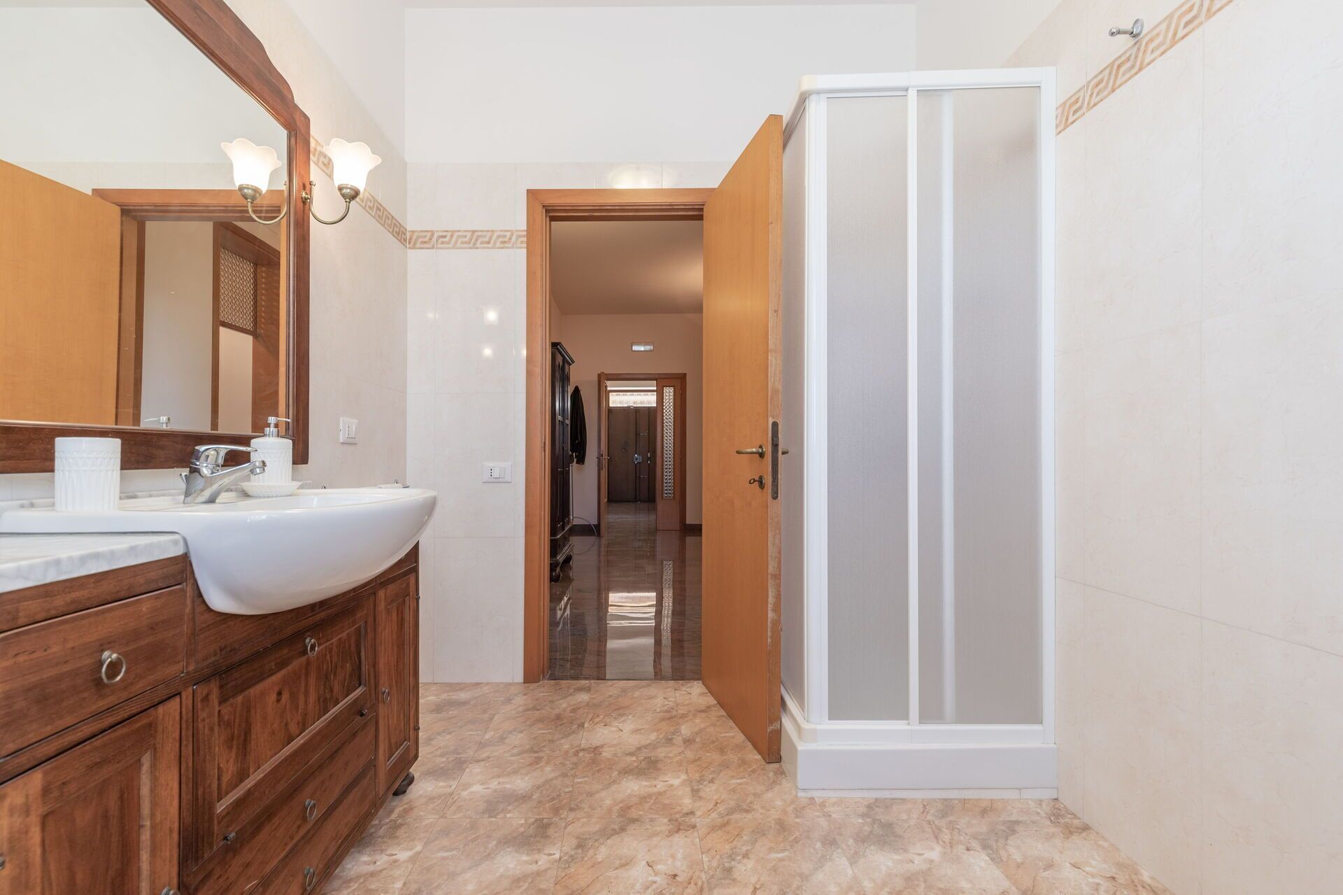 A bathroom with a wooden vanity, a large mirror, and a shower enclosure.