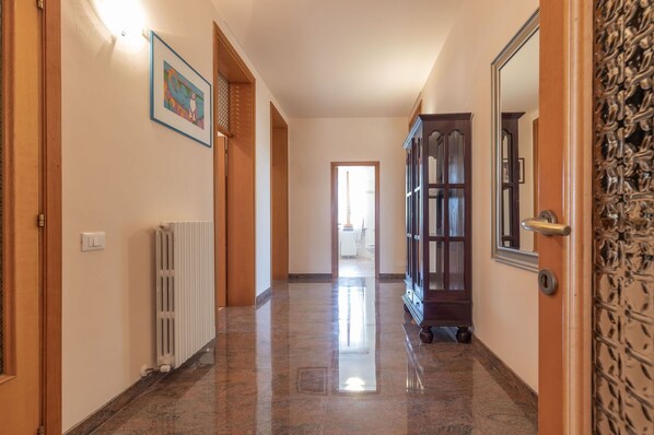 A hallway with a radiator, a framed picture on the wall, and a cabinet with a mirror.