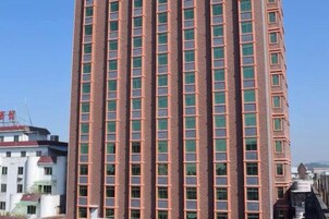Un edificio alto de ladrillo con una cuadrícula de ventanas.