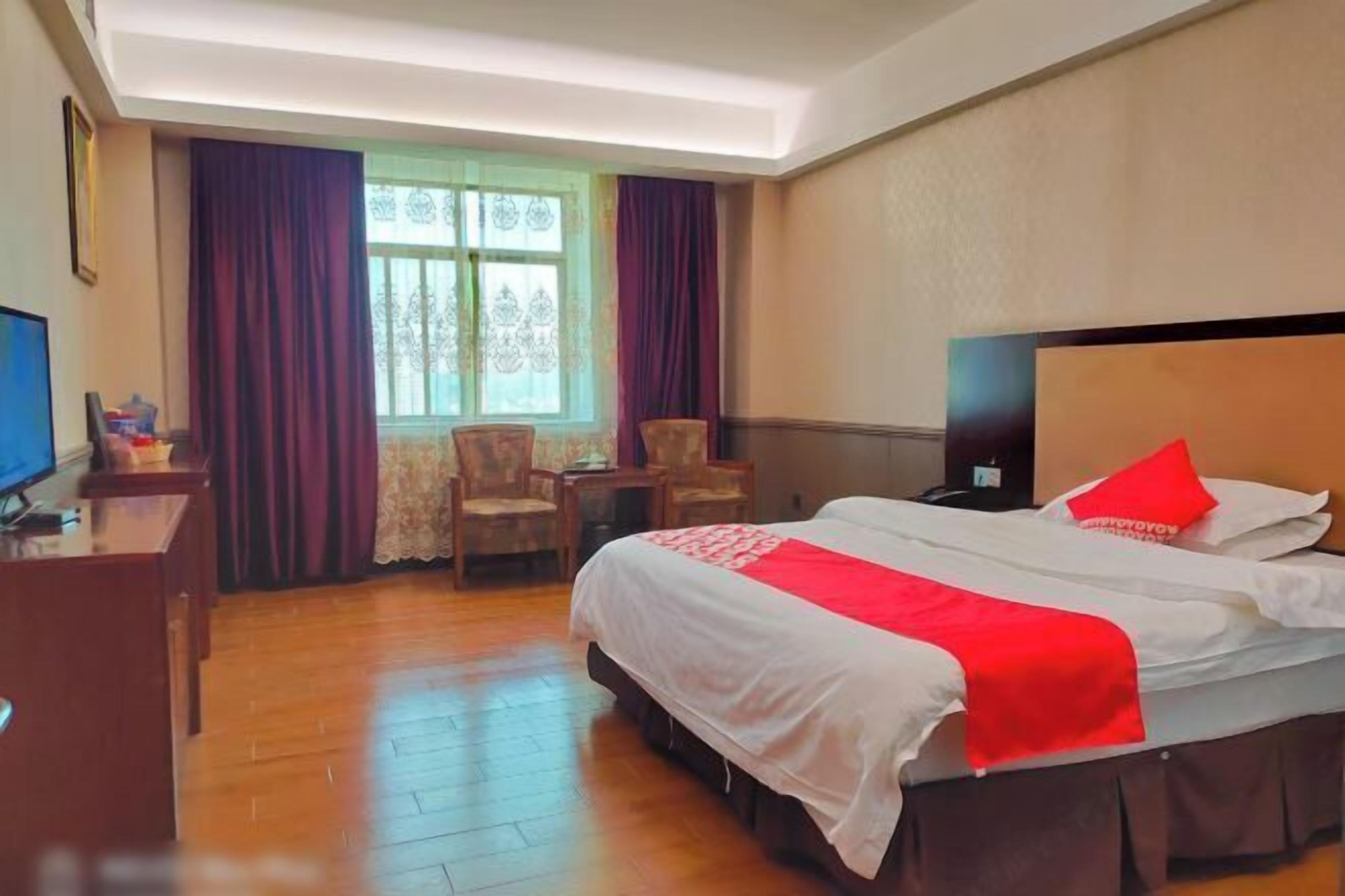 Una habitación de hotel con una cama grande, un escritorio, una silla y un televisor.