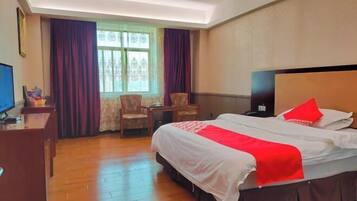 Una habitación de hotel con una cama grande, un escritorio, una silla y un televisor.