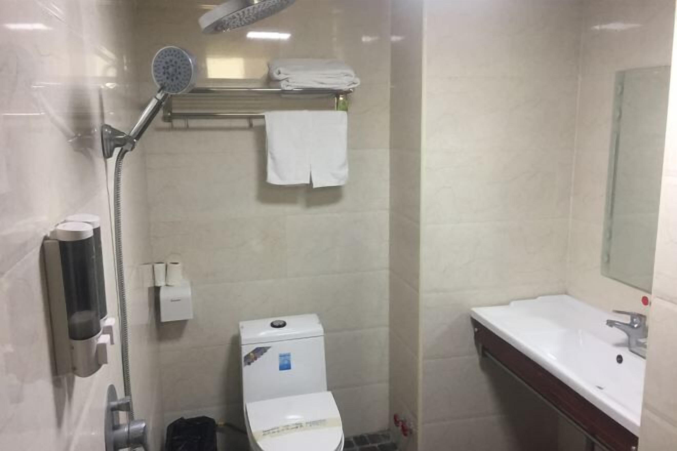 A small bathroom with a toilet, a shower, a sink, and a towel rack.