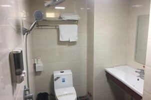 Un baño pequeño con inodoro, ducha, lavamanos y toallero.