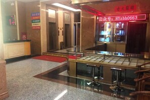 A hotel lobby with a reception desk, a glass display case, and a red neon sign. - Huayang Hotel (Puning)