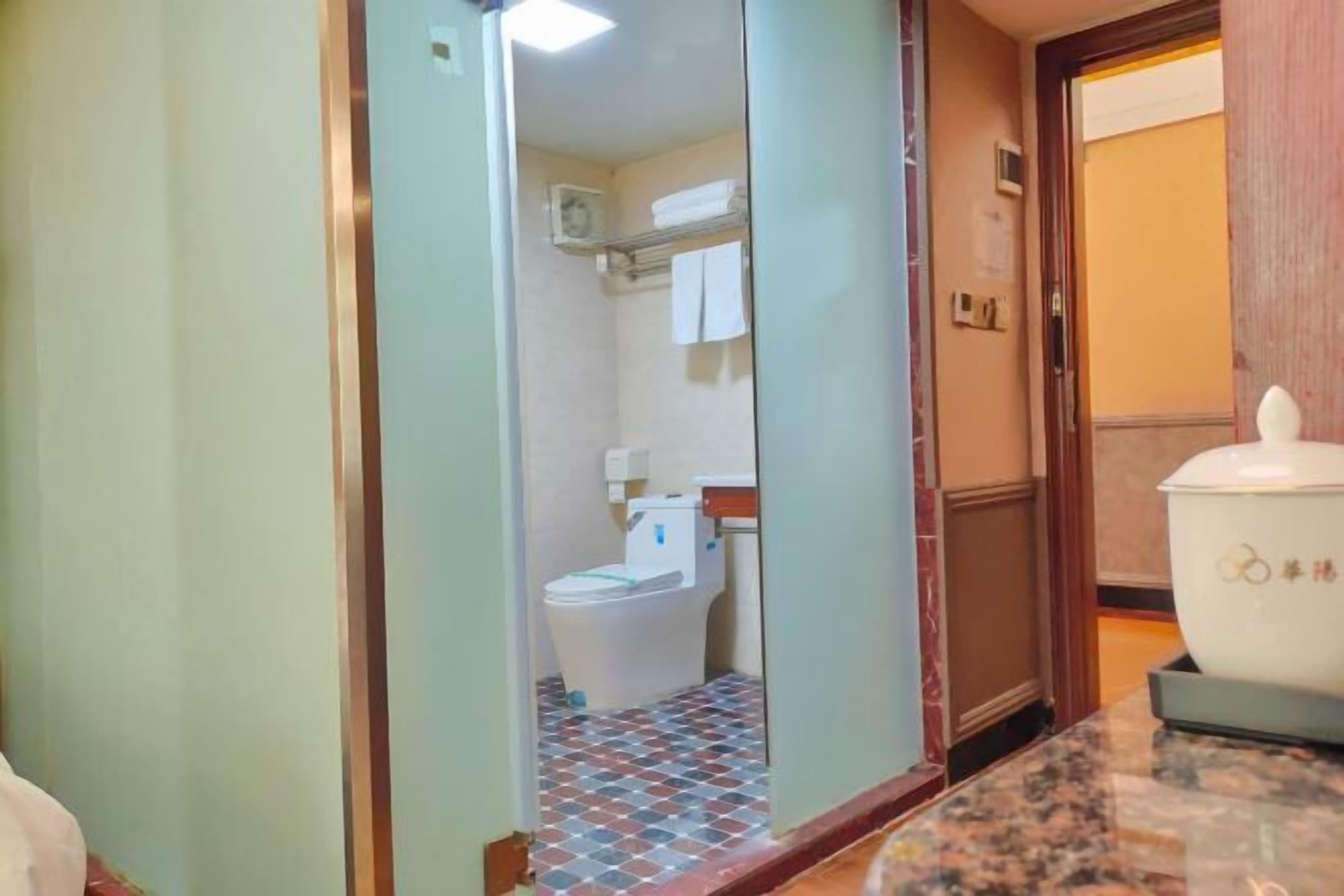 A hotel bathroom with a tiled floor, a toilet, and a sink.