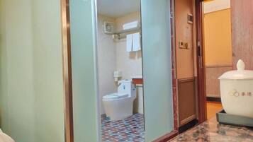 A hotel bathroom with a tiled floor, a toilet, and a sink.