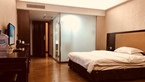 Habitación de hotel con cama, escritorio, dispensador de agua y espejo.