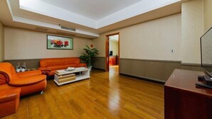 Una habitación amplia con piso de madera, un sofá, una mesita de centro y un escritorio.