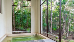 A room with a large window overlooking a forested area, a small pool, and a textured mat on the floor. - Bacalar Casa Relaxo on the Lagoon with Private Dock (Buenavista Bacalar)