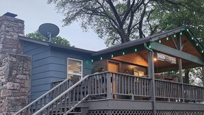Ett hus med en skorsten av sten, en satellantenn och en veranda med gröna lampor.