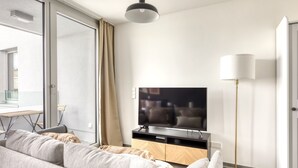 Ett modernt vardagsrum med en stor platt-TV, en soffa, ett soffbord och en golvlampa.