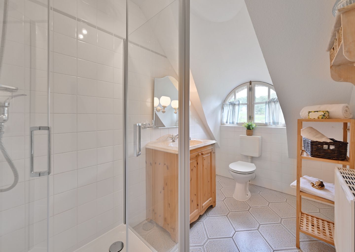A modern bathroom with a glass shower enclosure, a wooden vanity, a white toilet, and a small window.