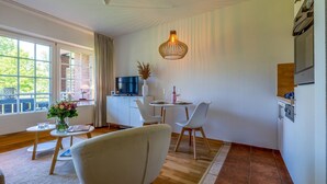 Una sala de estar moderna con televisor, comedor y un amplio ventanal.