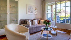 Un salón con sofá, sillón y una mesita con un florero.