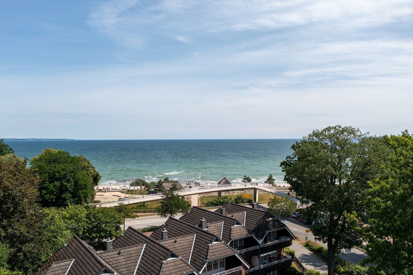 A coastal residential area with houses, a beach, and a bridge.