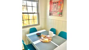 A dining area with a table set for two, featuring a fruit bowl, cheese, and bread.