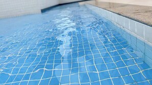 A swimming pool with a tiled floor and a concrete edge. - AxéHome | Charming Accommodation | 2 Bedrooms / 2 Bathrooms (Salvador)
