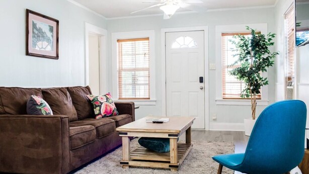A living room with a brown sofa, a wooden coffee table, a blue chair, and a potted plant. - 2 BD Quiet Neighborhood with AC, Desk, Fast Wifi (Torrance)