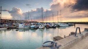 Ein Yachthafen mit vor Anker liegenden Booten, ruhigem Wasser und einem bewölkten Himmel.
