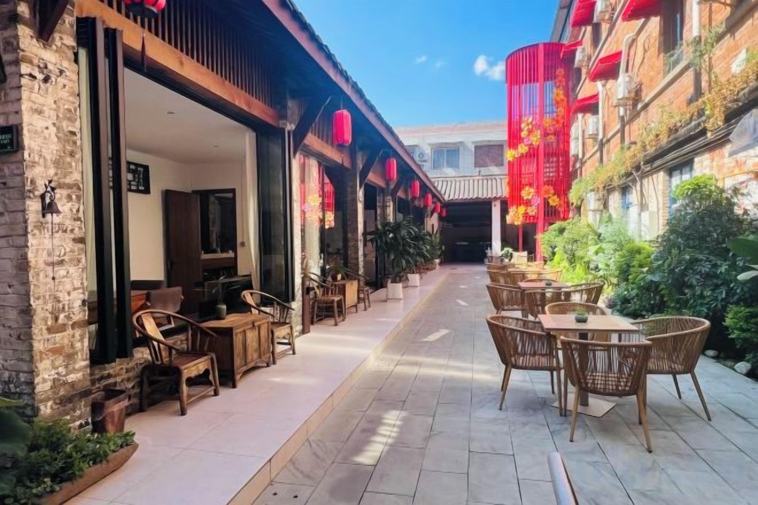 Un espacio al aire libre con mesas y sillas, un edificio de ladrillo y faroles rojos.