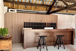 Una cocina moderna con armarios de madera, una isla central con taburetes y un techo inclinado con vigas a la vista.