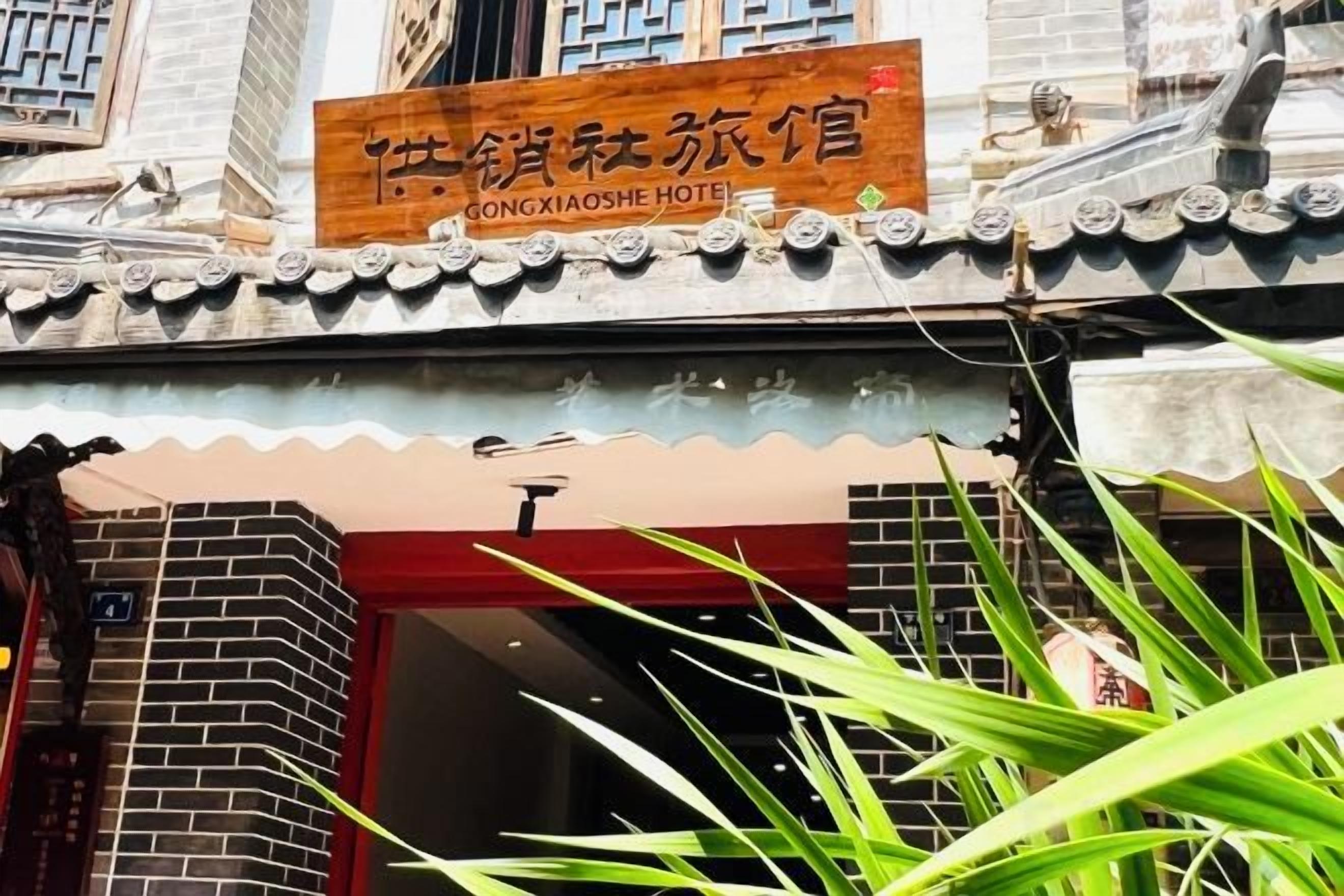 A hotel entrance with a traditional Chinese architectural style, a signboard with Chinese characters, and a red door.