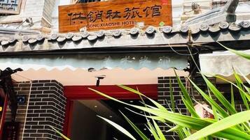 A hotel entrance with a traditional Chinese architectural style, a signboard with Chinese characters, and a red door.