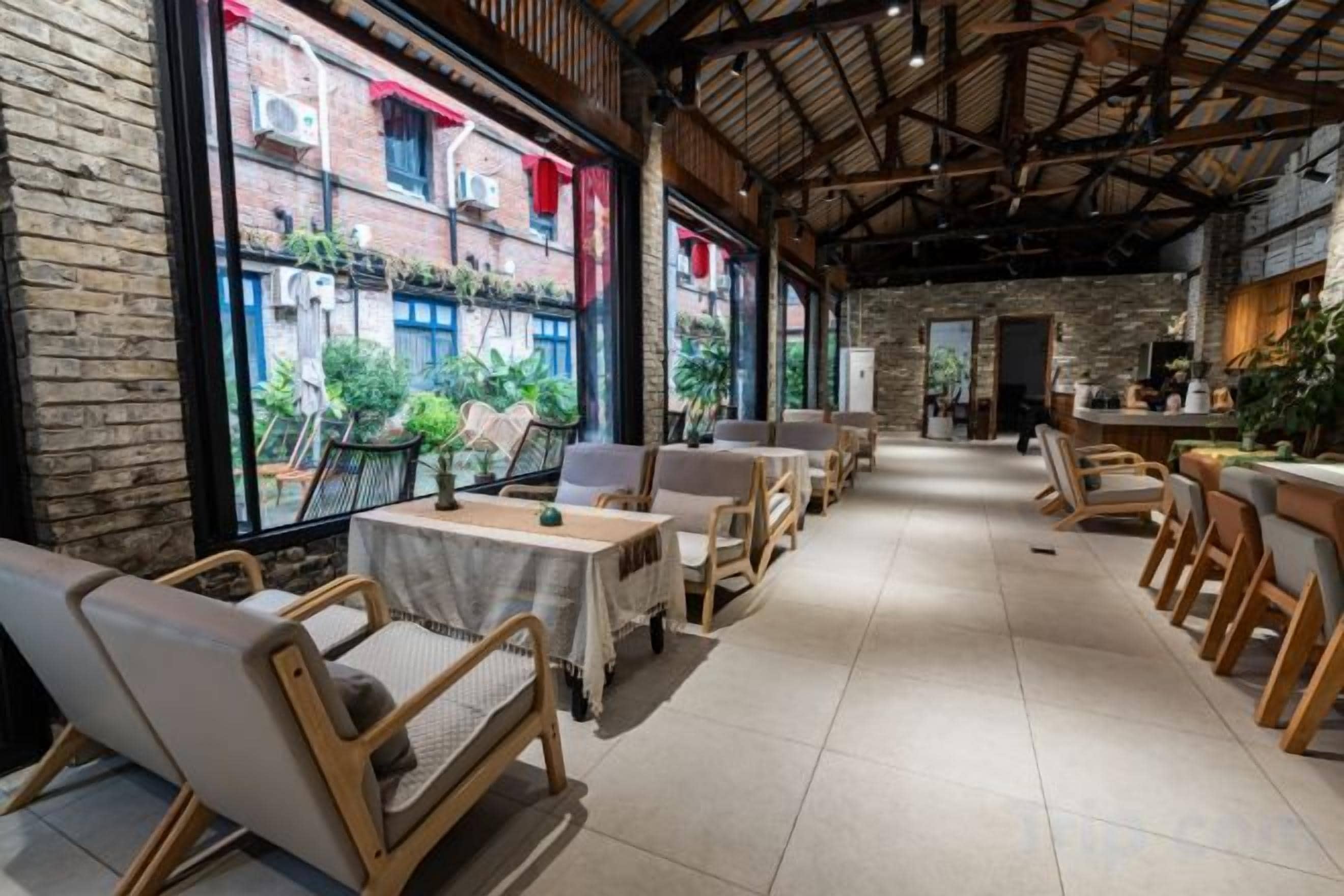 A restaurant with outdoor seating, brick walls, and a high ceiling.