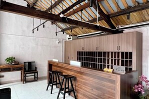 A kitchen with a wooden bar, stools, and a high ceiling with exposed beams. - Gongxiaoshe Inn (Luo Dai Ancient Town) (Chengdu)