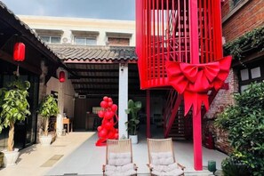 Un patio con una verja roja, plantas en macetas y una escalera.