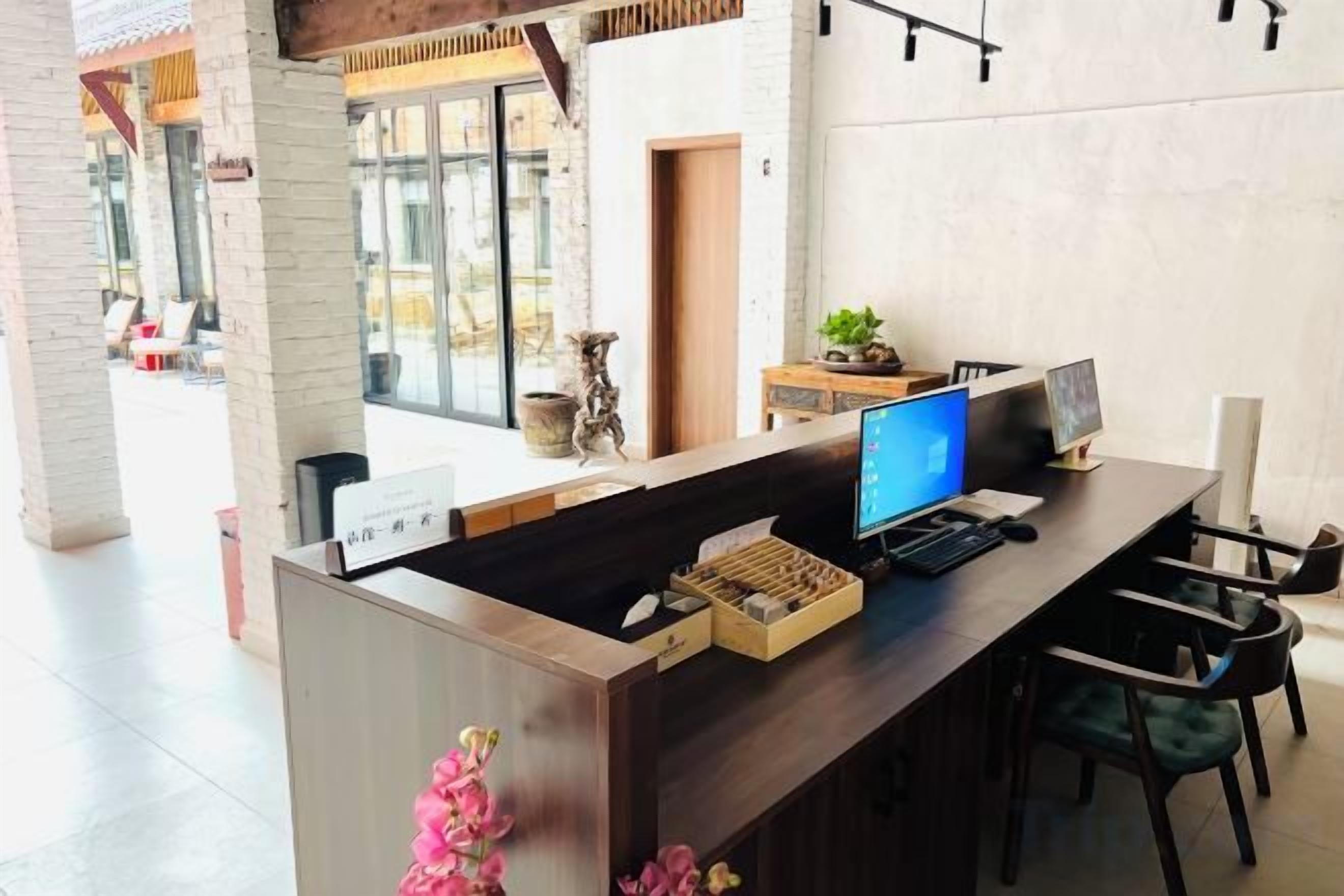 Una mesa de recepción con una computadora, una planta y un letrero.