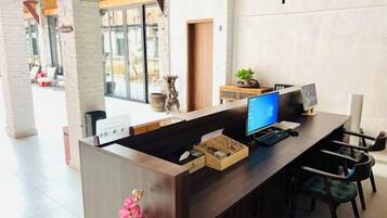 Una mesa de recepción con una computadora, una planta y un letrero.