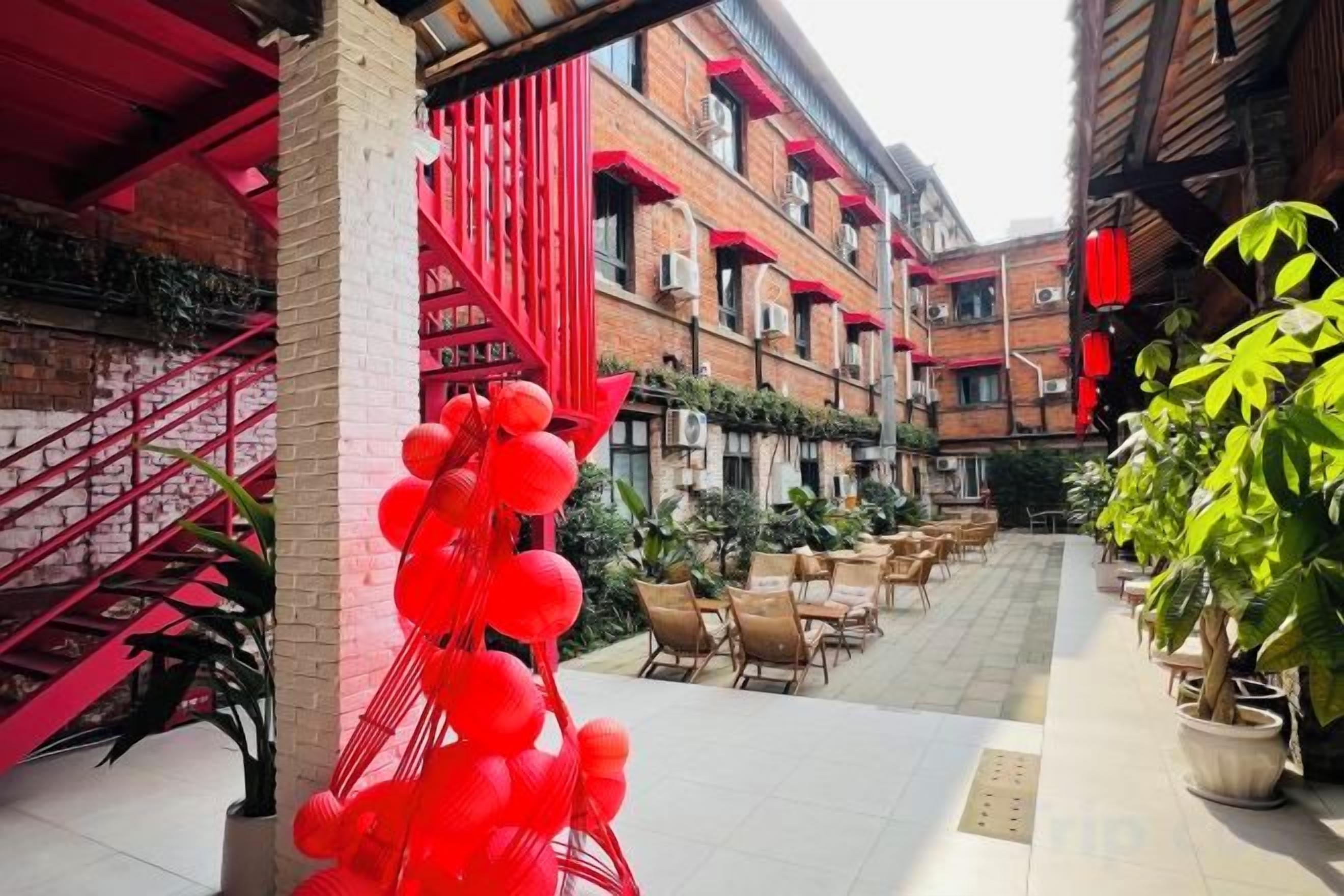 Un patio con mesas al aire libre, una escalera y una estructura decorativa roja.