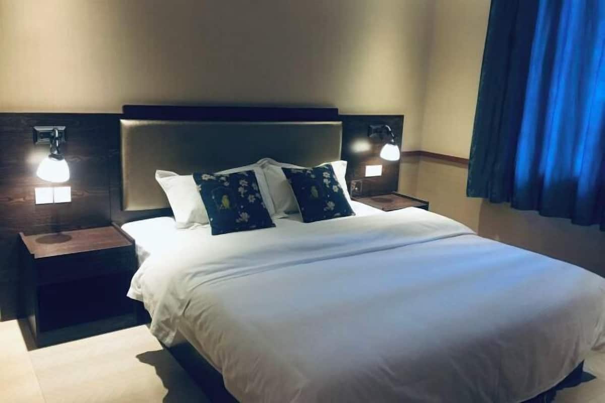 A neatly made bed with white linens and floral pillows, flanked by two bedside tables with lamps.