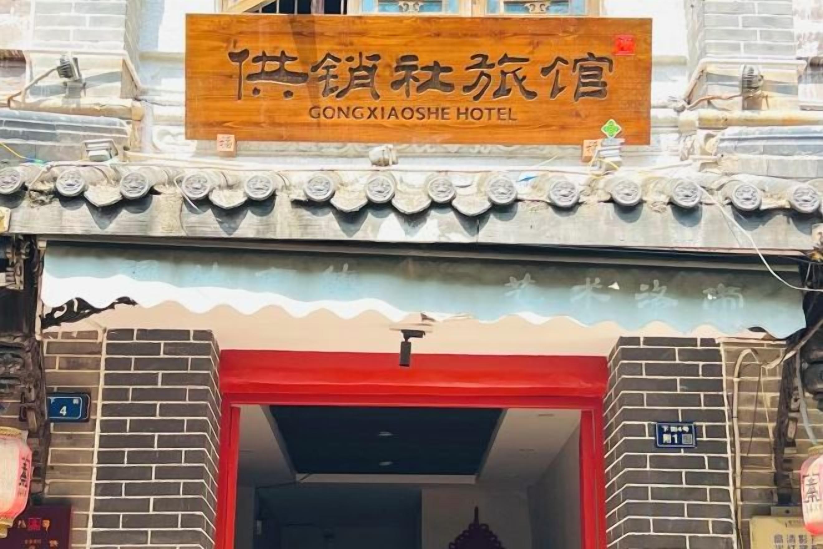 A hotel entrance with a traditional Chinese architectural style, a signboard above the entrance, and a red door.
