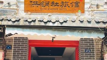 A hotel entrance with a traditional Chinese architectural style, a signboard above the entrance, and a red door.