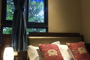 A bed with a headboard, two pillows with floral patterns, and a window with curtains. - Gongxiaoshe Inn (Luo Dai Ancient Town) (Chengdu)