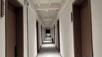 Un largo y estrecho pasillo de hotel con puertas a ambos lados, que conduce a habitaciones individuales.