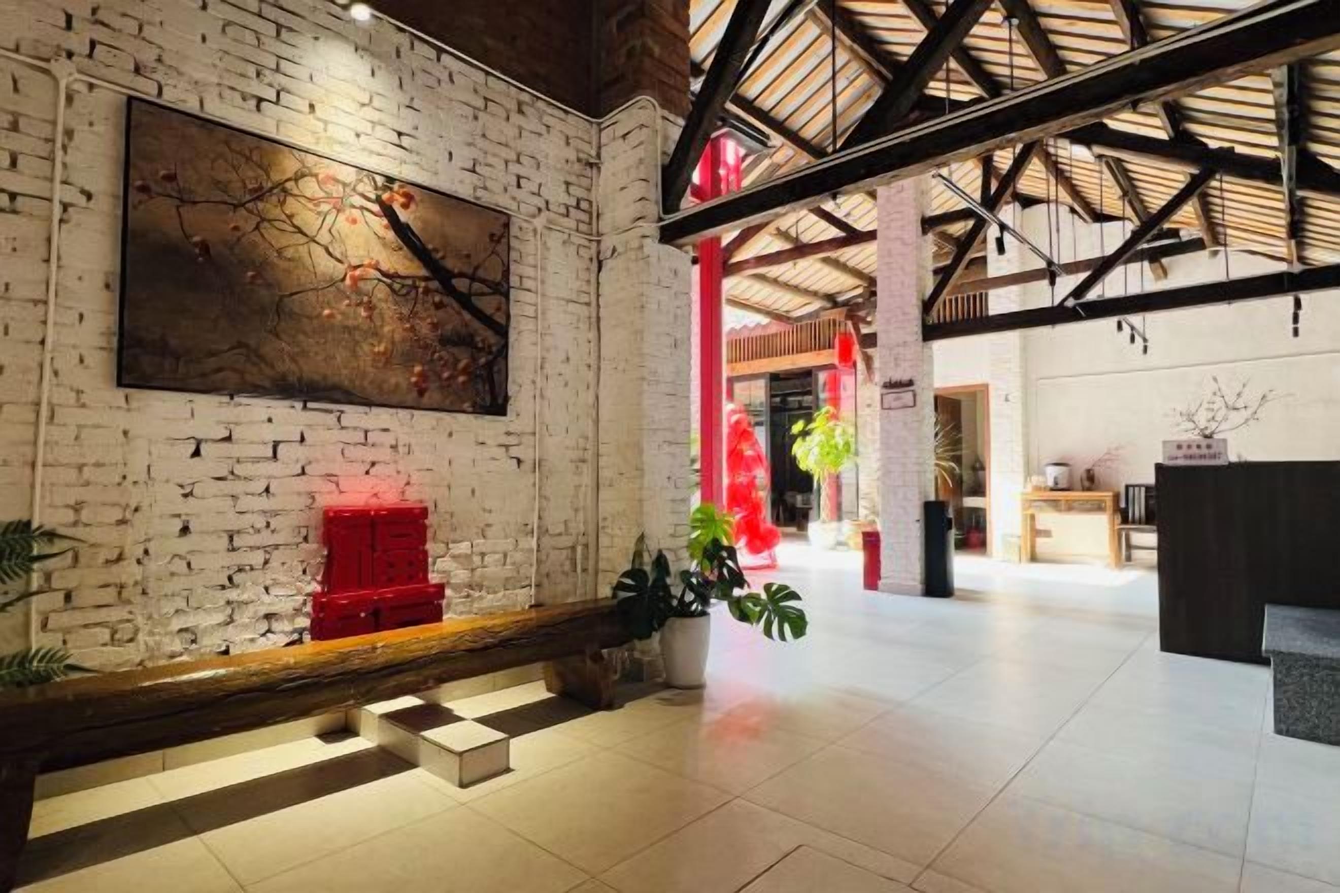 A spacious lobby with a brick wall, a reception desk, and a staircase leading to upper floors.
