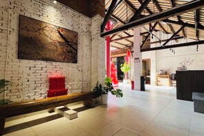 A spacious lobby with a brick wall, a reception desk, and a staircase leading to upper floors. - Gongxiaoshe Inn (Luo Dai Ancient Town) (Chengdu)
