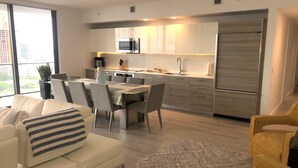 A modern kitchen with a dining area, a sofa, and a chair.