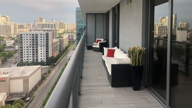 A balcony with a city view, modern furniture, and a potted plant.