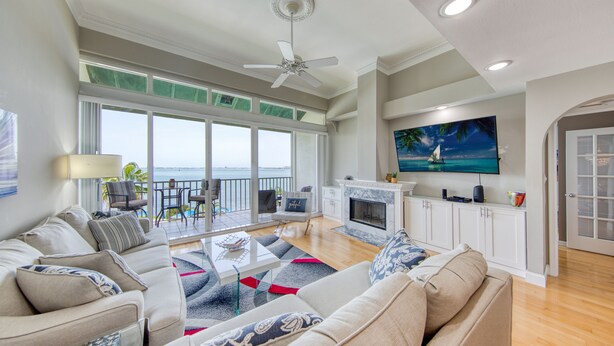 A spacious living room with a large sofa, a coffee table, and a fireplace. There is a balcony with a view of the ocean. - Paradise Penthouse (St. Petersburg)